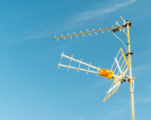 A low angle shot of a television antenna captured on a sunny day with a clear sky